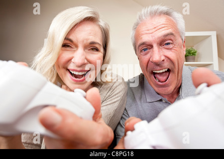 Couple, homme et femme, riant et s'amusant à jouer les jeux de console vidéo ensemble. Banque D'Images
