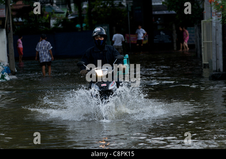 Bangkok lecteurs résidents moto à travers l'eau d'inondation de la Canal Phra Khanong débordante, Sukhumvit Road, soi 50, Bangkok, Thaïlande, le 30 octobre 2011. La Thaïlande connaît ses pires inondations en plus de 50 ans. crédit : Kraig Lieb Banque D'Images