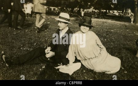 Vers 1910 Photo d'un homme et femme assise sur l'herbe à un festival. Banque D'Images