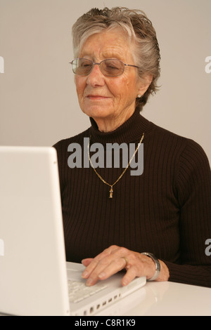 Une femme âgée à la recherche de son portable. Banque D'Images