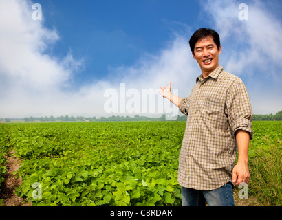 Happy asian farmer montrant sa ferme Banque D'Images