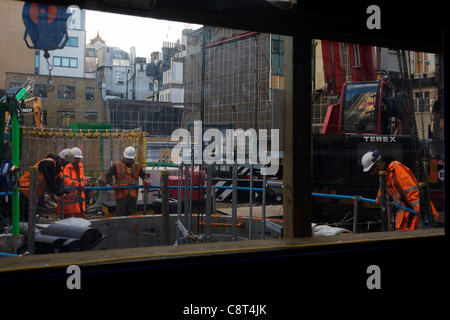 Ouvriers regarder vers le bas un grand trou faisant partie d'un projet de construction dans le centre de Londres. Banque D'Images