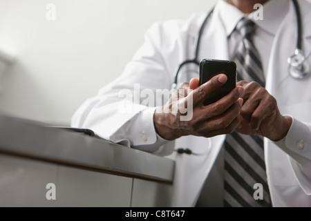 African American doctor text messaging on cell phone Banque D'Images