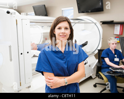 USA, Utah, Ogden, young female nurse standing in front of CAT scanner Banque D'Images