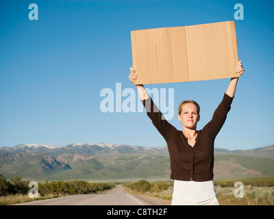 USA, Utah, Kanosh, Mid-adult woman de l'autostop dans un paysage aride Banque D'Images