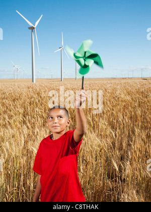 USA, Ohio, Wasco, Girl holding fan in wheat field with wind turbines in background Banque D'Images