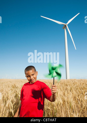 USA, Ohio, Wasco, Girl holding fan in wheat field with wind turbines in background Banque D'Images