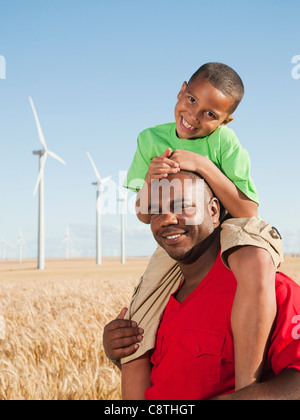 USA, Ohio, Wasco, Boy riding piggy-back sur le père, éoliennes en arrière-plan Banque D'Images