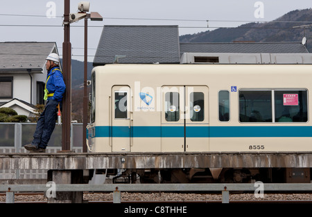 Un ouvrier se trouve près d'un train de la ligne Odaku à la gare de Shin Matsuda. Kanagawa, Japon. Banque D'Images