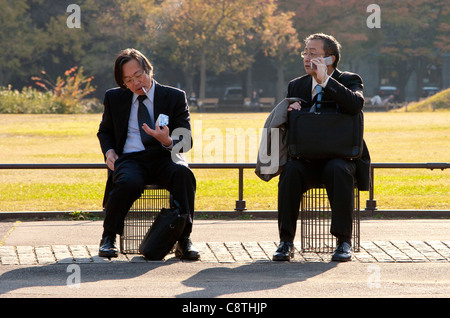 Salarymen japonais se reposant, fumant et parlant sur un téléphone portable dans le parc Hibiya. Tokyo, Japon. Banque D'Images