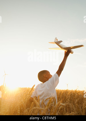 USA, Ohio, Wasco, boy playing with toy airplane in wheat field Banque D'Images