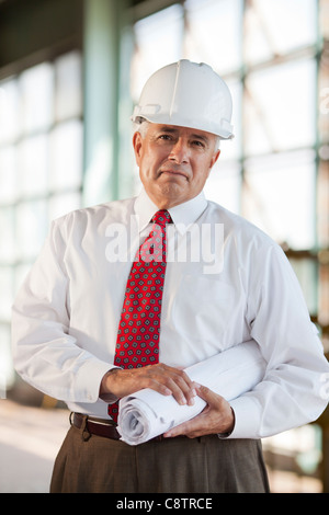 USA, New Mexico, Santa Fe, Portrait of senior man wearing hardhat et cravate, holding blueprint Banque D'Images