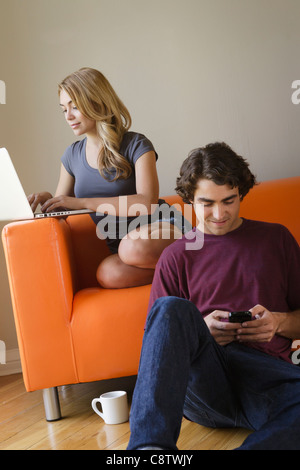 USA, Californie, Los Angeles, Jeune couple dans la salle de séjour, à l'aide de Phone et l'ordinateur portable Banque D'Images