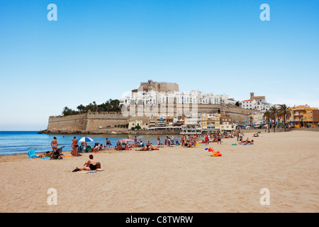 Les gens prennent le soleil sur une plage de sable près de la forteresse Peniscola. Peniscola, Communauté valencienne, Costa Del Azahar, Espagne. Banque D'Images