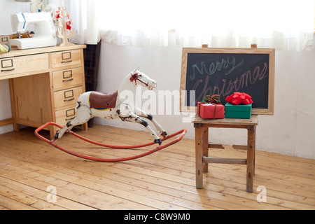 Chambre enfant intérieur avec des cadeaux de Noël et du cheval à bascule noir Banque D'Images