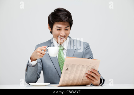 Businessman Reading Newspaper et Holding Coffee Cup Banque D'Images