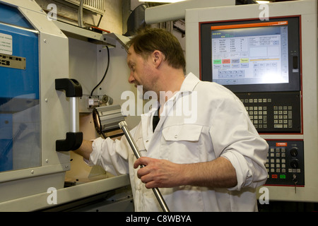 Vérifie les paramètres out ingénieur sur un tour CNC dans la tenue d'un atelier de l'arbre nouvellement fabriqués Banque D'Images