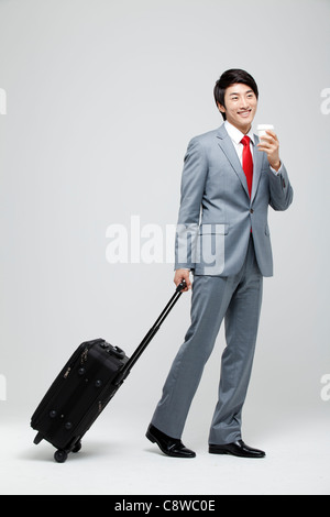 Asian Businessman Walking With Luggage Holding café à emporter Banque D'Images