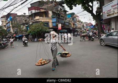 Vendeur de rue de Hanoi transportant un 'traditionnels' ganh quang bandoulière pour le transport, la vente de l'ananas. Vietnam Banque D'Images