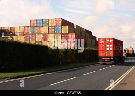 Un camion conteneur passant un conteneur de stockage à Felixstowe, Suffolk, Angleterre Banque D'Images