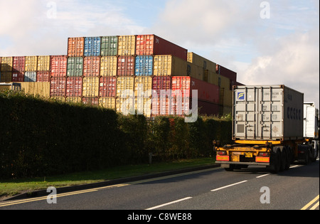 Un camion conteneur passant un conteneur de stockage à Felixstowe, Suffolk, Angleterre Banque D'Images