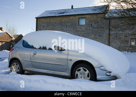 Couverte de neige voiture garée sur le bord de la route après les fortes chutes de neige en hiver. En Angleterre, Royaume-Uni, Grande Bretagne. Banque D'Images