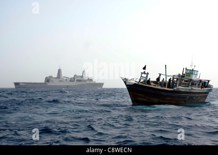 USS Mesa Verde (LPD 19) attend dans la distance comme une équipe de marins aller à bord d'un boutre de handicapés. Banque D'Images