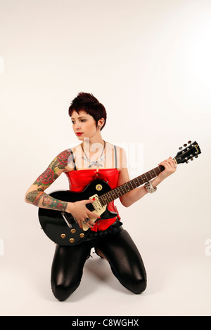 Fille avec des tatouages sur son bras tenant une guitare électrique Banque D'Images