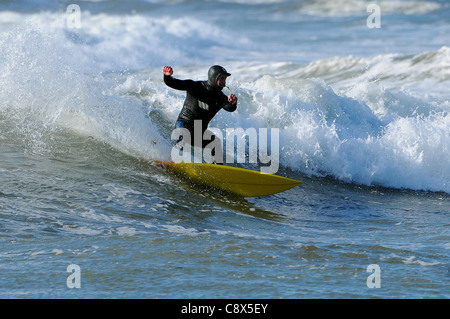 Manèges d'un surfer une vague au large de la plage de Bantham de Devon au cours du mois de novembre. Banque D'Images