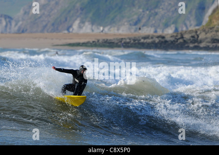 Manèges d'un surfer une vague au large de la plage de Bantham de Devon au cours du mois de novembre. Banque D'Images