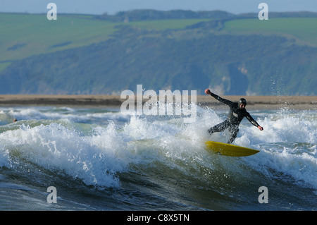 Manèges d'un surfer une vague au large de la plage de Bantham de Devon au cours du mois de novembre. Banque D'Images