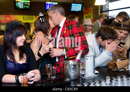 Un couple dans un bar kiss célèbre après un pari gagnant sur une course de chevaux à l'hippodrome de Cheltenham Banque D'Images