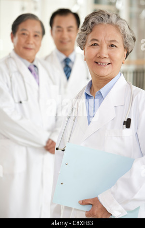 Senior Female Doctor avec deux médecins en arrière-plan Banque D'Images