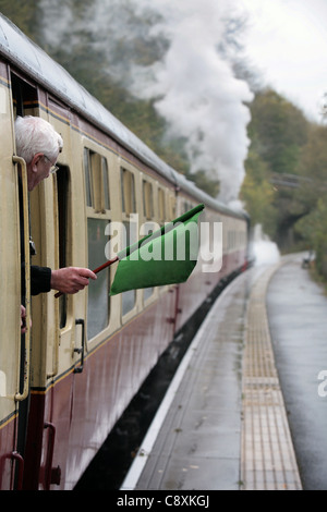 Un wavws garde son drapeau de l'arrière d'une locomotive à vapeur sur le chemin de fer Weardale, Parkhead Station, comté de Durham. UK. Banque D'Images