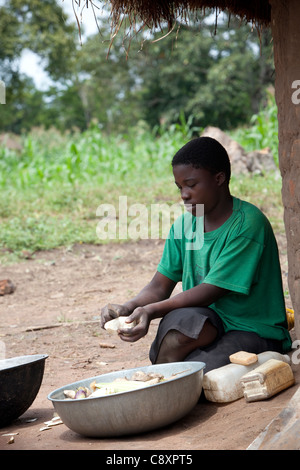 Une femme épluche les patates douces récoltés dans le jardin de sa famille dans le district de Kibuku, en Ouganda. Banque D'Images