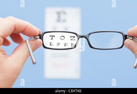 Mains tenant en avant des yeux Lunettes graphique, studio shot Banque D'Images