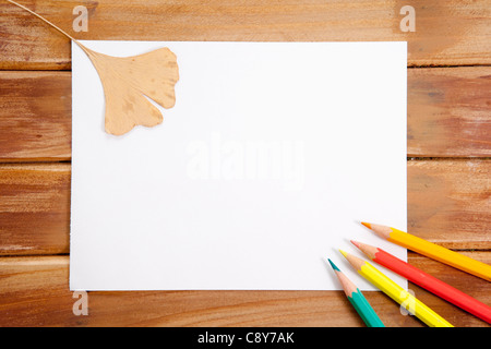 Quatre Crayons de couleur et une feuille tombée sur papier blanc Banque D'Images