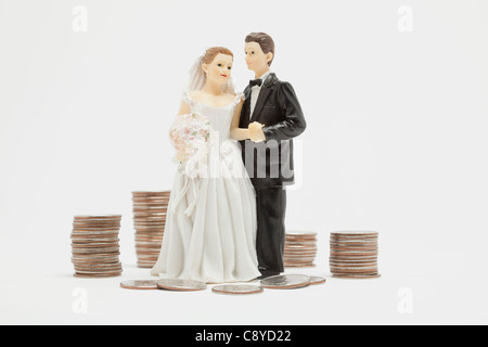 Figurines de mariage et des piles de pièces, studio shot Banque D'Images