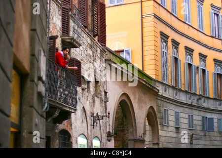 Jeune homme sur le balcon donnant sur la ville médiévale de Sienne, Toscane Italie Banque D'Images