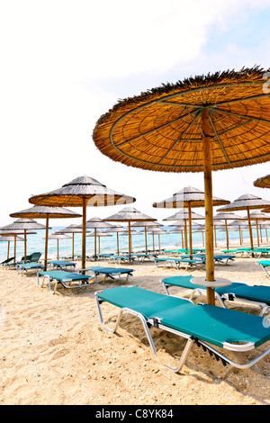 Des parasols de paille sur la plage en bord de vide en Grèce Banque D'Images