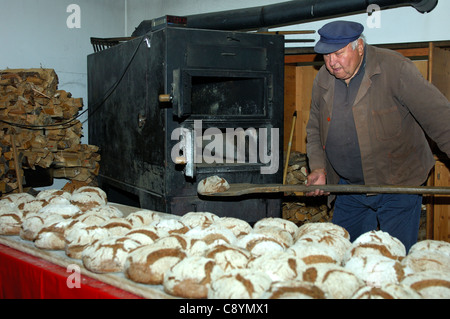 Baker mise hors des pains de seigle Valaisian du four de la boulangerie du village à Erschmatt, Valais, Suisse Banque D'Images