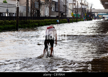 La bicyclette à travers l'eau d'inondation en centre-ville de Bangkok, Thaïlande Banque D'Images