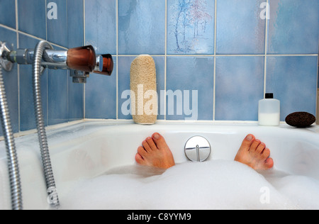 Le bain. Pieds sortant de l'eau à la fin d'une baignoire Banque D'Images