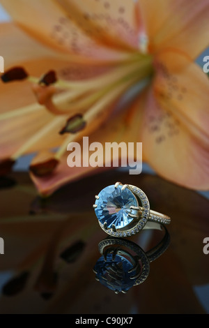 Bague en or avec un grand joyau de la surface de mise en miroir et d'un grand lys orange sur un arrière-plan Banque D'Images