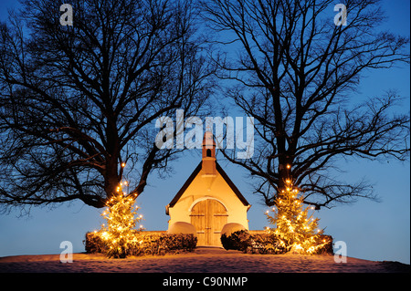 Chapelle illuminée avec deux arbres de Noël illuminés, le lac de Chiemsee, Chiemgau, Upper Bavaria, Bavaria, Germany, Europe Banque D'Images