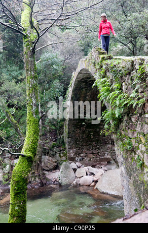 Les jeunes femmes marchant sur le pont génois dans le canyon des gorges de Spelunca, près de Porto et Ota, Corse, France Banque D'Images