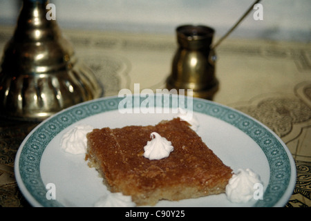 Un Basbousa sweetmeat du Moyen-Orient avec la tasse de café en laiton Banque D'Images