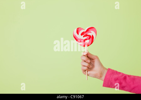 Girl (10-11) holding heart shaped lollipop Banque D'Images