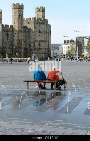 Deux dames âgées se détendre sur un banc de la place du château de Caernarfon gwynedd North Wales UK Banque D'Images