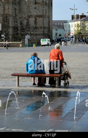 Deux dames âgées se détendre sur un banc de la place du château de Caernarfon gwynedd North Wales UK Banque D'Images